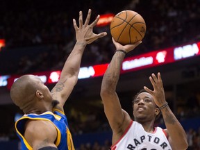 Toronto's DeMar DeRozan (right) shoots over Golden State's David West during pre-season play on Oct. 1.