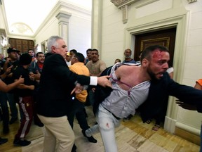 An opposition deputy struggles while pro-government supporters force their way to the National Assembly during an extraordinary session called by opposition leaders, in Caracas on Sunday.