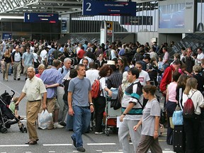 British Airways tailfins are seen in the background as crowds settle in for a long wait at Terminal 4 at Heathrow Airport in London, 11 August 2005, as thousands of people are stranded.