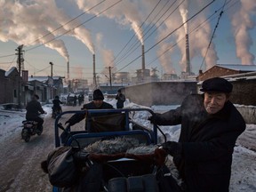 Chinese men pull a tricycle near a coal-fired power plant in Shanxi, China, in 2015.