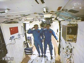 Two Chinese astronauts Jing Haipeng, left and Chen Dong salute in the space lab Tiangong 2. The astronauts have entered China’s orbiting space station for a month-long stay.