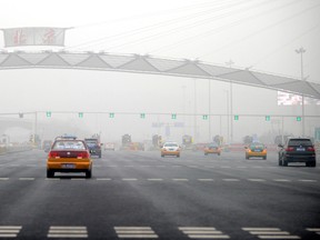 Cars pass through toll booths on a highway covered in haze in Beijing in 2011.