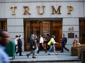 Pedestrians walk past the Trump building at 40 Wall Street near the New York Stock Exchange
