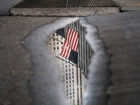 An American flag is reflected in a puddle outside of the New York Stock Exchange.