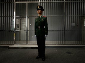 A paramilitary guard stands before the bars of a main gate to the No.1 Detention Center in Beijing on October 25, 2012