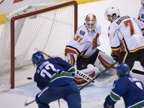 Daniel Sedin of the Canucks puts a shot past Flames goalie Chad Johnson as Calgary defenceman TJ Brodie looks on during third period action in Vancouver on Saturday night.