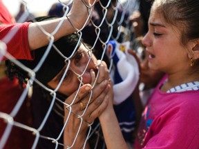 A newly displaced Iraqi woman kisses a child's hand as she is reunited with her relatives at a refugee camp in the Khazer area on Wednesday.