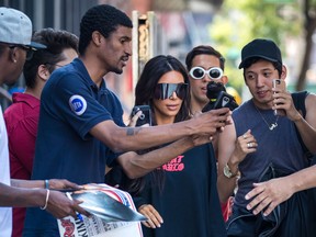 A paparazzi shot of Kim Kardashian, surrounded by fans and oglers on the street.