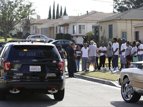 Los Angeles Police officers stop their patrol vehicle to speak to neighbours and members of the community gathered around a makeshift memorial outside a residence on Sunday, Oct. 2, 2016.