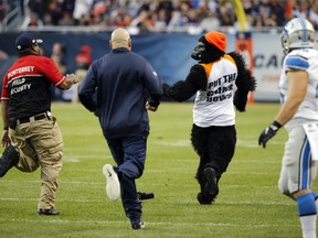 A fan is chased by security personnel on the field during the second half of an NFL football game between the Chicago Bears and the Detroit Lions, Sunday, Oct. 2, 2016, in Chicago.