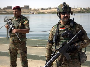 In this Saturday, Oct. 15, 2016 file photo, Iraqi soldiers secure a temporary pontoon bridge near Qayara Air Base, northern Iraq.