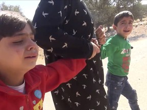 This frame grab from video provided by Muaz al-Shami, Syrian Revolution Network shows children pulled by an adult after airstrikes killed over 20 people, mostly children, in the northern rebel-held village of Hass, Syria