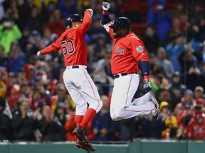 Mookie Betts, left, high-fives David Ortiz after Ortiz hits a seventh-inning game-winning homerun for the Boston Red Sox in Friday's 5-3 victory over the Toronto Blue Jays at Fenway Park.