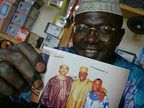 This 2004 file photo shows Malik Obama, the  half brother of President Barack Obama, who holds an undated picture of Barack, left, and himself, centre, and an unidentified friend in his shop in Siaya, Kenya. He says he will vote for Donald Trump.