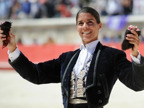 French "Rejoneadora" Lea Vicens holds up the ears of a fighting bull during the Pentecost feria Bullfight in Nimes, southern France, on May 25, 2015.