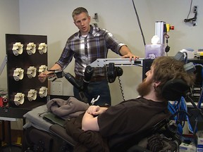 University of Pittsburgh Medical Center researcher Robert Gaunt touches the finger of a robotic arm, causing Nathan Copeland, a quadraplegic, to feel that sensation in his own finger.