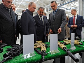 Russian President Vladimir Putin, second from left, with Defence Minister Sergei Shoigu, centre, examine a display of rifles while visiting a Kalashnikov plant in the city of Izhevsk on Sept. 20, 2016.