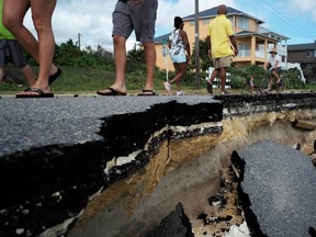 Local residents walk on a part of closed A1A highway washed out by Hurricane Matthew in Flagler Beach, Florida on the weekend.