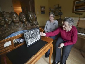 Cécile Dionne (right), with her sister Annette (they are the two surviving Dionne quintuplets, born in Ontario in 1934), places a photo of themselves and their sisters when they were children onto a a desk at the St. Bruno home of Annette.