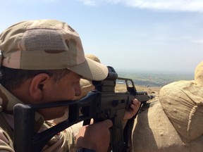 In a 2015 photo, a Kurdish peshmerga keeps watch for ISIL fighters dug in 800 metres away. Canadian Special Forces have been training the Kurdish forces.