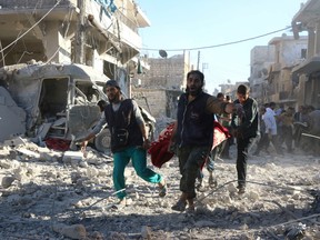 Rescuers carry wounded people to safety after Syrian government airstrikes on the rebel-held neighbourhood of Heluk in Aleppo, on Sept. 30