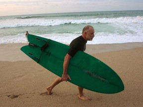 In this Dec. 2, 2015, Jody Meacham, of New Jersey, emerges from an evening surfing session at the main beach in Sayulita, Mexico. The once tranquil fishing town of Sayulita has matured to a top travel and retirement destination in Mexico. (AP Photo/Manuel Valdes)