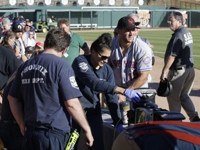 Scottsdale Scorpions outfielder Tim Tebow, center, comforts a fan, on ground, who was suffering a seizure, following Tebow's debut against the Glendale Desert Dogs in a baseball game Tuesday, Oct. 11, 2016, during the Arizona Fall League in Glendale, Ariz.