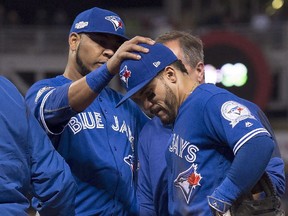The Blue Jays' Edwin Encarnacion, left, consoles Devon Travis as he leaves with an injury during the fifth inning in Game 1 of the American League Championship Series on Friday, Oct. 14, 2016.