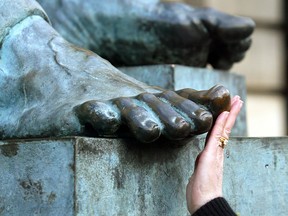 A woman touches the toe of the bronze statue of Scottish philosopher David Hume in Edinburgh, Scotland. Passersby rub the shiny big toe for luck.