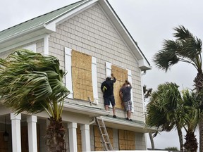 Workers put plywood over windows of a home in preparation for Hurricane Matthew Wednesday, Oct. 5, in Ponte Vedra Beach, Fla.