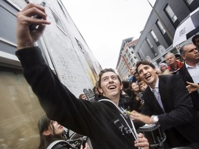 Prime Minister Justin Trudeau, right, takes a selfie with students from Laura Secord Secondary School during a visit in St. Catharines, Ont., on Friday, October 21, 2016.