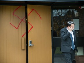 Joshua Dougherty wipes his eye as he comes through the doors at Congregation Machzikei Hadas at 2310 Virginia Dr which was spray painted with swastikas and foul racial messages sometime over the night.