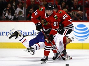 Patrick Kane of the Chicago Blackhawks controls the puck as Andrew Shaw of the Montreal Canadiens hits the ice at the United Center on Sunday in Chicago. The Blackhawks defeated the Canadiens 3-2.