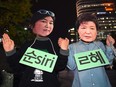 Protestors wearing masks of South Korean President Park Geun-Hye (R) and her confidante Choi Soon-Sil (L) at a rally denouncing a scandal over President Park's aide in Seoul on October 27, 2016