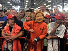 A child dressed in a mock Hillary Clinton mask and prison suit (C) listens as Republican Presidential nominee Donald Trump addresses a capacity crowd at the Jefferson County Fairgrounds - Rodeo Arena & Event Center in Golden, Colorado on October 29, 2016