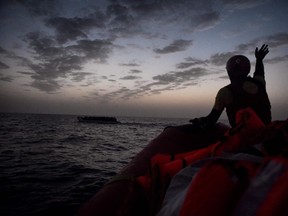 A file photo of a rescuer waving to a boat of migrants off the coast of Libya