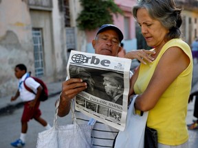 Cubans read a newspaper with its front page informing of the victory of US presidential candidate Donal Trump in a street of Havana, on November 9, 2016.