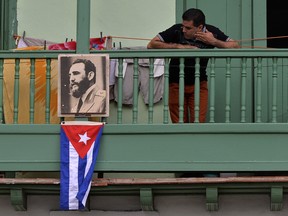 A man remains in a balcony next to a picture of Cuban revolutionary leader Fidel Castro at San Francisco de Asis Square in Havana, on November 27, two days after Castro's death.
