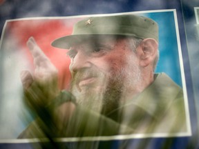 An image of Cuban longtime leader Fidel Castro is seen through flowers displayed at the entrance of the Cuban embassy in Beijing on November 29, 2016, four days after Castro's death.