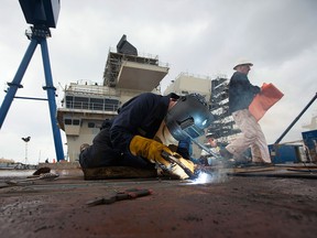 A worker welds a hatch door on the flight deck of Britain's new Queen Elizabeth class aircraft carrier, manufactured by an alliance that includes BAE Systems, at Babcock shipyard in Rosyth, U.K., on March 25, 2014.