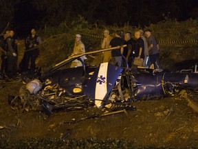 Police gather at a military helicopter which crashed in Rio de Janeiro, Brazil on Saturday, Nov. 19, 2016. The aircraft had been providing support to a police operation in the Cidade de Deus "City of God" slum.
