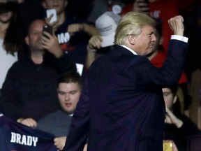 A supporter (left) holds a Tom Brady jersey as Donald Trump leaves the stage after a campaign rally on Monday in Manchester, N.H.