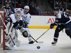 Colorado Avalanche goalie Calvin Pickard watches the puck as Avalanche defenceman Fedor Tyutin  defends Vancouver Canucks right winger Alexandre Burrows during the second period of an NHL hockey game, Saturday in Denver.