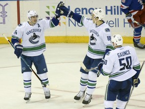 Vancouver Canucks' Alexandre Burrows, left, celebrates his goal with teammates Nikita Tryamkin, centre, and Brendan Gaunce during the third period of their game against the Rangers on Tuesday night at Madison Square Garden in New York. The Canucks won 5-3.