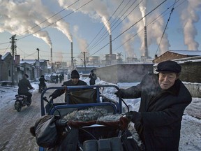 Chinese men pull a tricycle in a neighbourhood next to a coal-fired power plant in Shanxi, China, on Nov. 26, 2015.