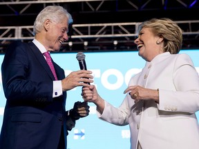 Democratic presidential candidate Hillary Clinton hands a microphone to her husband, former president Bill Clinton, at a campaign event in North Las Vegas on Oct. 19, 2016, following the third presidential debate.