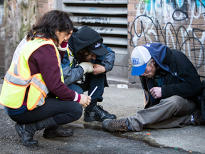 Volunteers tend to a possible overdose victim near an unsanctioned injection site in Vancouver on Monday.