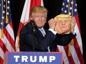 Republican presidential nominee Donald Trump holds up a rubber mask of himself during a campaign stop in  Sarasota, Fla., on Monday.