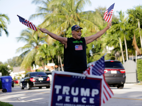 A Donald Trump supporter waves American flags as he stands outside his Miami home on election day, Nov. 8, 2016.