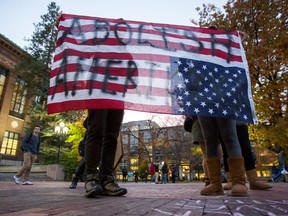 Two people hold an American Flag upside down, which reads, "Abolish Amerikkka" during an anti-Trump rally at the Diag on the University of Michigan's campus on Wednesday, Nov. 9. A woman was threatened for wearing a hijab just outside of the campus.